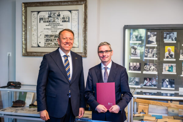 Dr hab. Mateusz Folwarski, prof. UEK, prezentuje dokument powołania na Kierownika Katedry Bankowości i Globalnego Systemu Finansowego, stojąc obok JM Rektora UEK dr. hab. Bernarda Ziębickiego, prof. UEK.