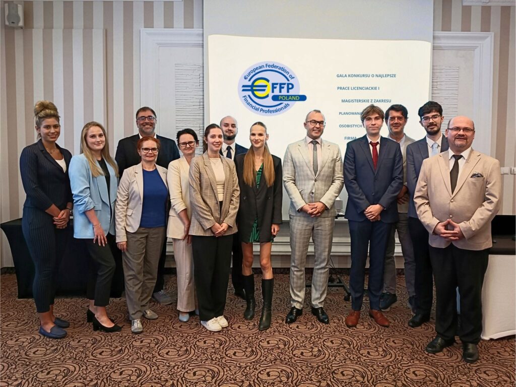 Grupa jedenastu osób w strojach biznesowych pozuje do wspólnego zdjęcia przed ekranem z logo i informacjami o wydarzeniu.